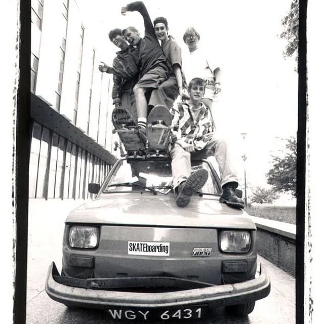 Ekipa skaterów na dachu i masce Polskiego Fiata 126p z naklejką SKATEboarding, czarno-białe zdjęcie archiwalne